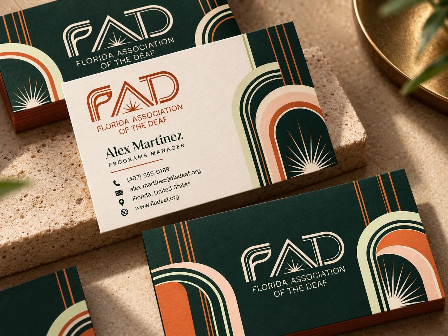 Art Deco business cards: deep green and cream cards with the line FAD and sunburst wordmark, stacked arches in orange, peach, and green, and a cream card with contact details.